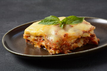 Homemade delicious Meat lasagna with basil leaf on the top.  italian Lasagna with bachamel sauce on gray background. Hot tasty Lasagna with cheese