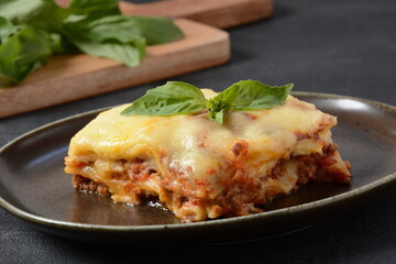 Homemade delicious Meat lasagna with basil leaf on the top.  italian Lasagna with bachamel sauce on gray background. Hot tasty Lasagna with cheese
