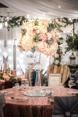 Wedding breakfast table romantic floral centre piece. Beautiful flowers in vase decorating luxury marriage celebration table.