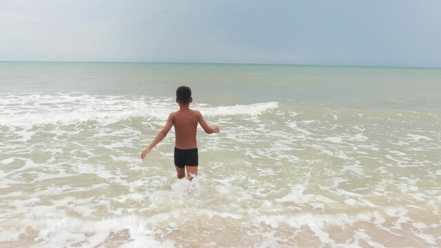 child running on the seashore with waves