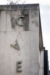 Letter A falling down hanging from side of derelict abandoned old 1970's concrete building. Sign dropping off wall.