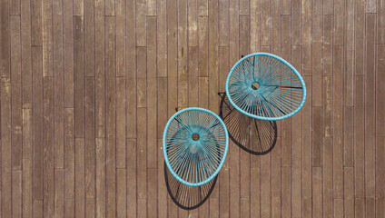 Aerial. Summer wicker chairs on the wooden terrace board. Top view from drone. Minimalistic summer background with copy space.