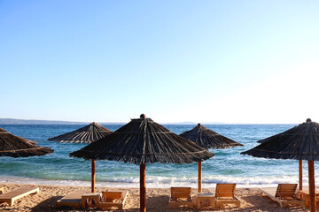 Bamboo parasol and wooden deck chair on a beautiful beach in Croatia.