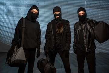 Three thieves in black outfit carrying handbags with stolen stuff - obrazy, fototapety, plakaty