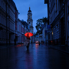 A woman with an umbrella on a city street at night in the light of red lanterns