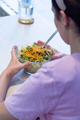 Healthy eating, dieting and people concept - close up of young woman eating vegetable mixed salad in restaurant, in dining table. Woman eating fresh salad 