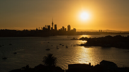 Auckland city in silhouette with the sun in the sky, photo taken from North Head in Devonport,...