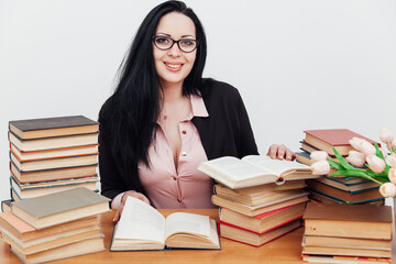 beautiful business woman in business suit at a table with stacks of educational books