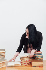 beautiful female teacher in business suit at a table with stacks of educational books