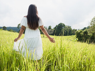 Woman in white dress stand in meadow beautiful nature with tree,valley and cloudy on sky,Girl travel in nature at holiday freshness and sunlight