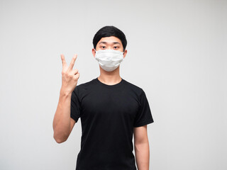 Asian man black shirt with mask show two finger counting on white isoated background