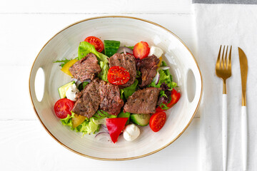 Fillet of beef with vegetable salad on wooden table