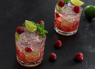 Bourbon or rum raspberry smash cocktail with lime and mint. Refreshing cold drink. dark background,...