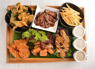 giant appetiser platter combo with mini hot dog, mushroom soup, deep fried tempura prawn, sliced wagyu beef, fish skin with salted egg yolk, french fries on banana leaf wood board party halal menu