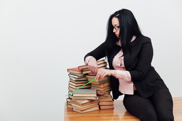 beautiful female teacher in class at a table with stacks of educational books