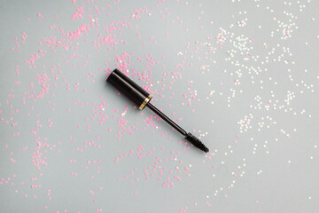 Mascara brush for eye lash extension and confetti on trendy gray background. Beauty minimal...