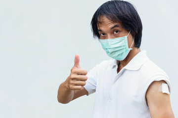 asian man get vaccinated of covid-19 and show his thumb up sign.