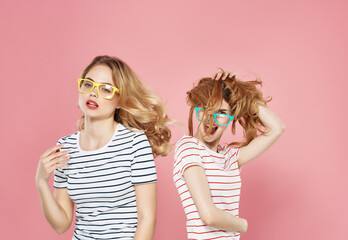 two girls standing side by side in striped t-shirts friendship pink background fashion