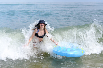Cute girl being hit by a wave playing on sea beach