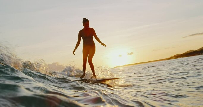 Beautiful Hawaiian surfer girl riding ocean wave at sunset, active lifestyle adventure outdoors