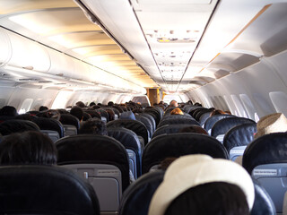 Interior of a plane with passengers on their seats .