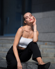 Blonde in the city in a white top and heels