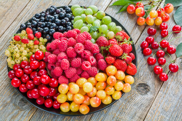 Fresh ripe berries laid out on a plate on a wooden table