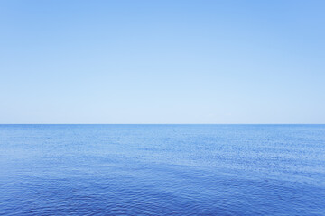 Obraz premium a calm blue lake against a clear sky with a horizon and a space for text.