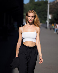Fototapeta premium Blonde outdoors in white top, black pants and heels
