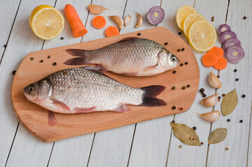 Fresh fish, lemon and other ingredients on the kitchen board