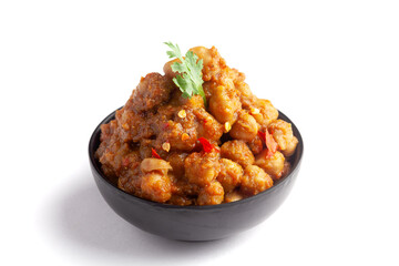 Chickpeas masala (Spicy chola or chhole curry)  garnished with fresh green coriander and ingredients. Served in a black bowl. A Classic Indian typical Panjabi street food.  In white background