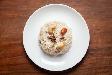 Obraz na płótnie Canvas Indian Basmati Rice or Kasmiri pulao (pulav) or Dry Fruits Pulao garnished with dry fruits and spices in a black bowl