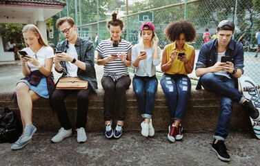 Young adult friends using smartphones together outdoors youth culture concept - obrazy, fototapety, plakaty