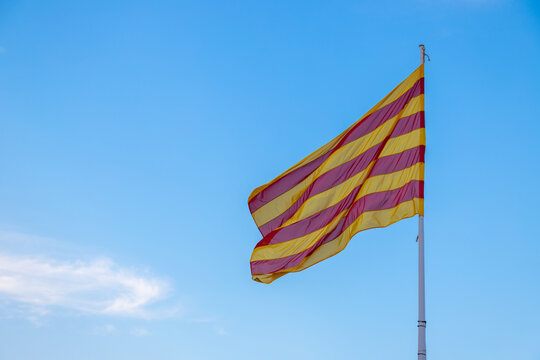 Catalan Flag ("Senyera") in a pole moved by the wind under a blue sky.