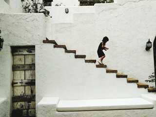 Side View Of Child Walking On Staircase Against Building