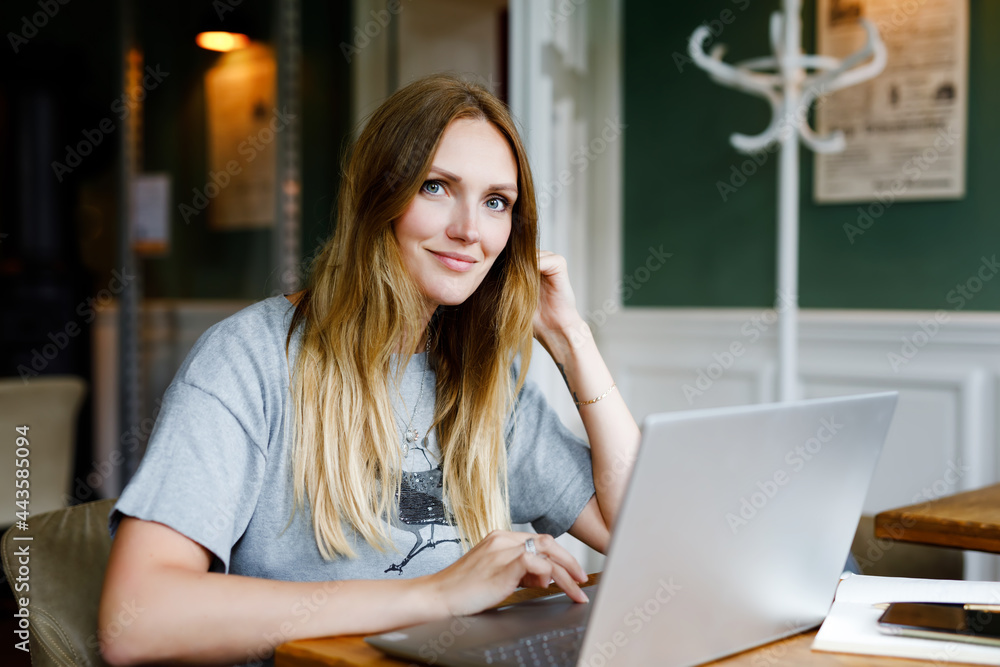 Wall mural portrait of young woman using technology of smartphone and looking at laptop. young woman freelancer