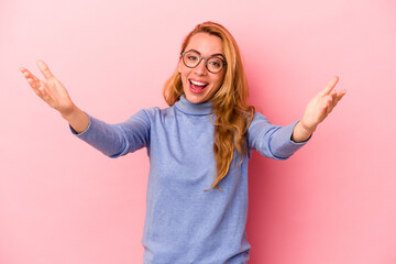 Caucasian blonde woman isolated on pink background celebrating a victory or success, he is surprised and shocked.