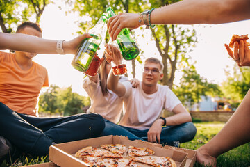 Friends drink beer and alcohol and eat pizza outdoors, hands close-up