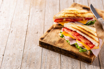 Sandwich with tomato,lettuce,ham and cheese on wooden table. Copy space