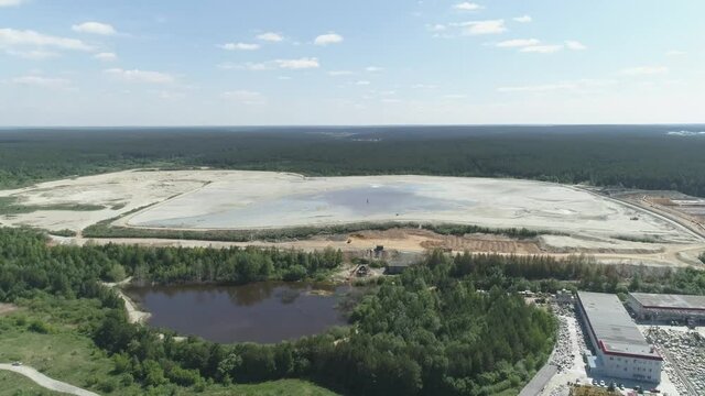 Aerial view of Huge sand dumps from a gold mine. Near the forest, the village and the river. A summer sunny day
