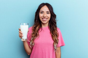 Young mixed race woman holding a glass of milk isolated on blue background happy, smiling and cheerful.