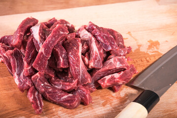 Marbled beef cut into strips on a board with a knife, close-up
