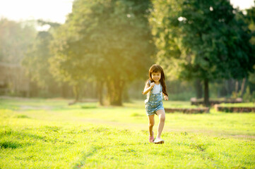 Obraz premium Little girl running on meadow nature outdoors in country field summer sunset.