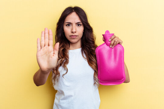 Young mixed race woman holding a hot bag isolated on yellow background standing with outstretched hand showing stop sign, preventing you.