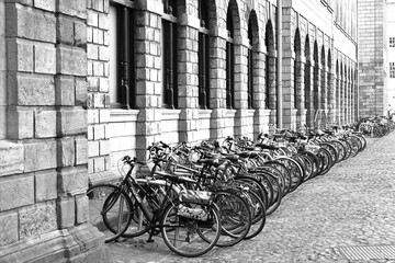 Vélos alignés à Dublin en Irlande le long d'un bâtiment ancien en pierre.  Cliché en noir et blanc 