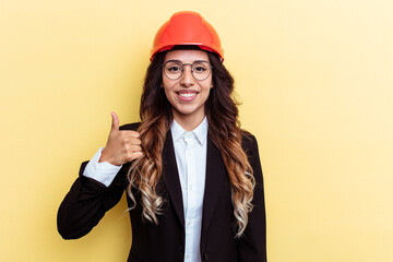 Young architect mixed race woman isolated on yellow background smiling and raising thumb up