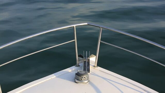 bow of a white yacht with iron chrome handrails and a chain with an anchor on the background of sea waves on the way of a voyage of an expensive ship during vacation, nobody.