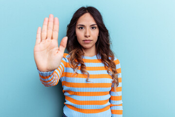 Young mexican woman isolated on blue background standing with outstretched hand showing stop sign, preventing you.