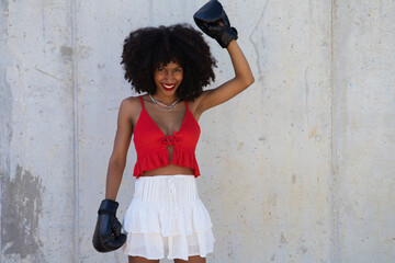 Beautiful Afro-American woman with boxing gloves claiming women's rights against mistreatment and breast cancer. Concept of women's rights.