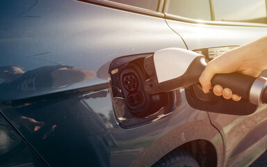 Man hand is holding Electric car charging connect to elecric car on charge station, Electric...